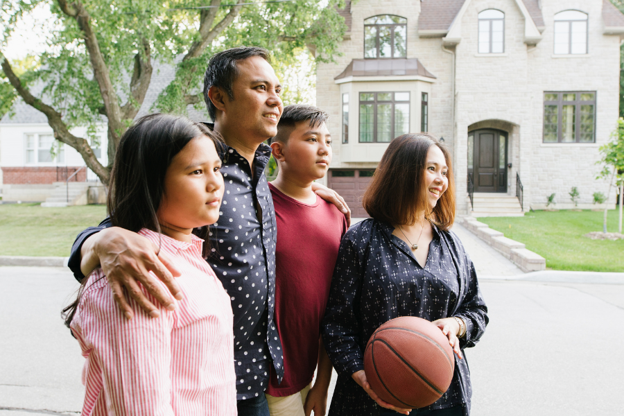 Newcomer family standing outside their home with basketball