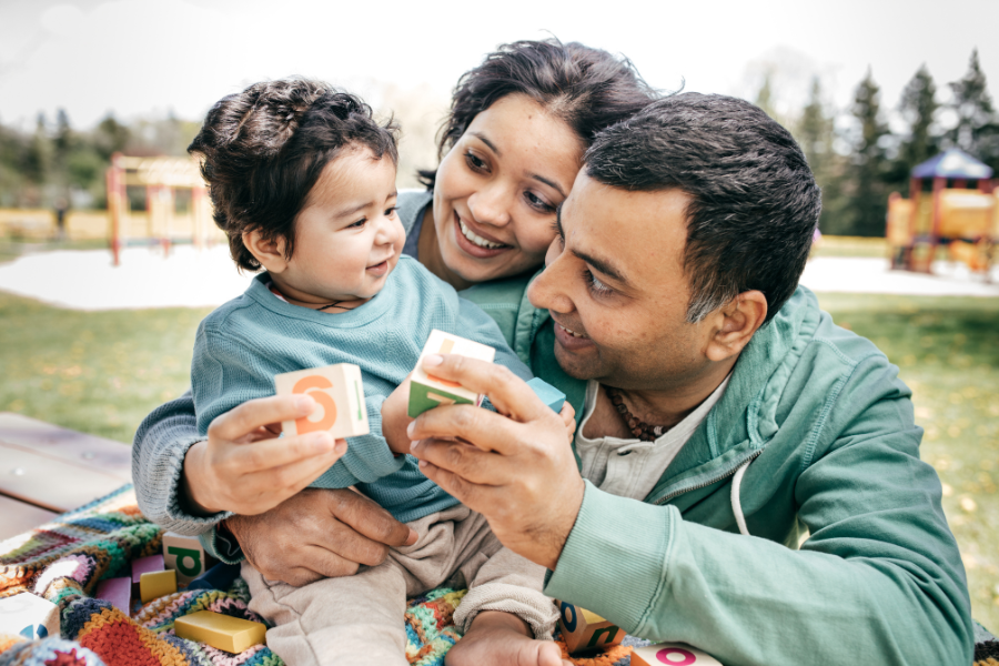 Parents and toddler playing with blocks at a picnic table