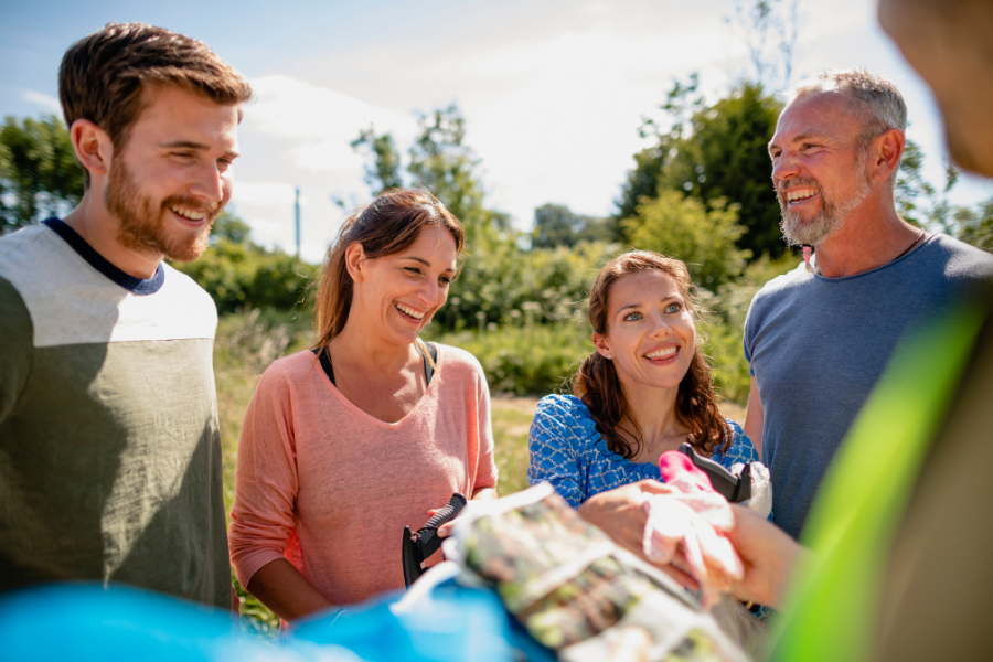 Group of adult volunteers smiling and chatting outdoors