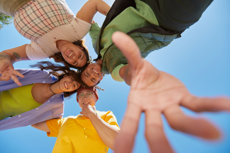 Diverse youth huddled together smiling under a blue sky
